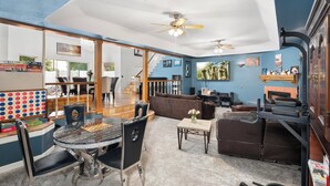 A spacious living room with a fireplace, a ceiling fan, and a large TV.