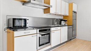 A modern kitchen with white cabinets, stainless steel appliances, and wooden accents.