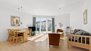 A modern living room with a wooden dining table, a sofa, and a TV.