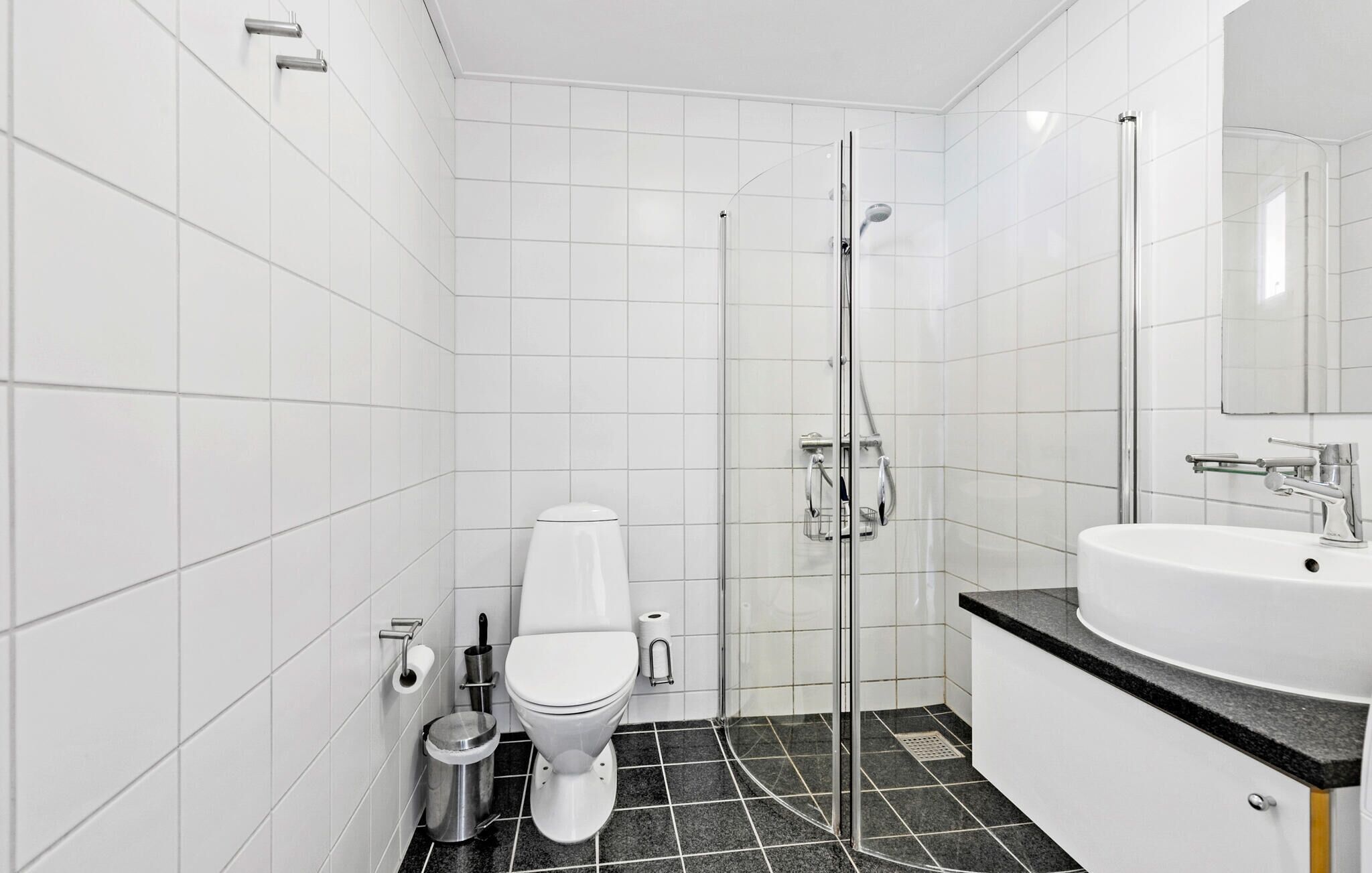 Une salle de bain moderne équipée de toilettes, d’une douche à parois de verre et d’un lavabo avec un miroir.