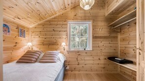 A cozy cabin room with a bed, two bedside lamps, a window with a view of trees, and a shelf with a book. - 3 bedroom gorgeous home in Skals (Skals)