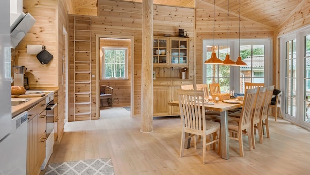 A wooden cabin interior with a dining area, kitchen, and a large window offering a view of the outdoors. - 3 bedroom gorgeous home in Skals (Skals)