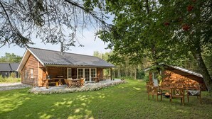 A wooden cabin with a porch and a small deck, surrounded by a grassy yard and trees. - 3 bedroom gorgeous home in Skals (Skals)