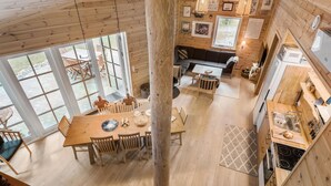 A spacious dining area with a wooden table and chairs, a kitchen with wooden cabinets and a sink, and large windows offering a view of the outdoors. - 3 bedroom gorgeous home in Skals (Skals)