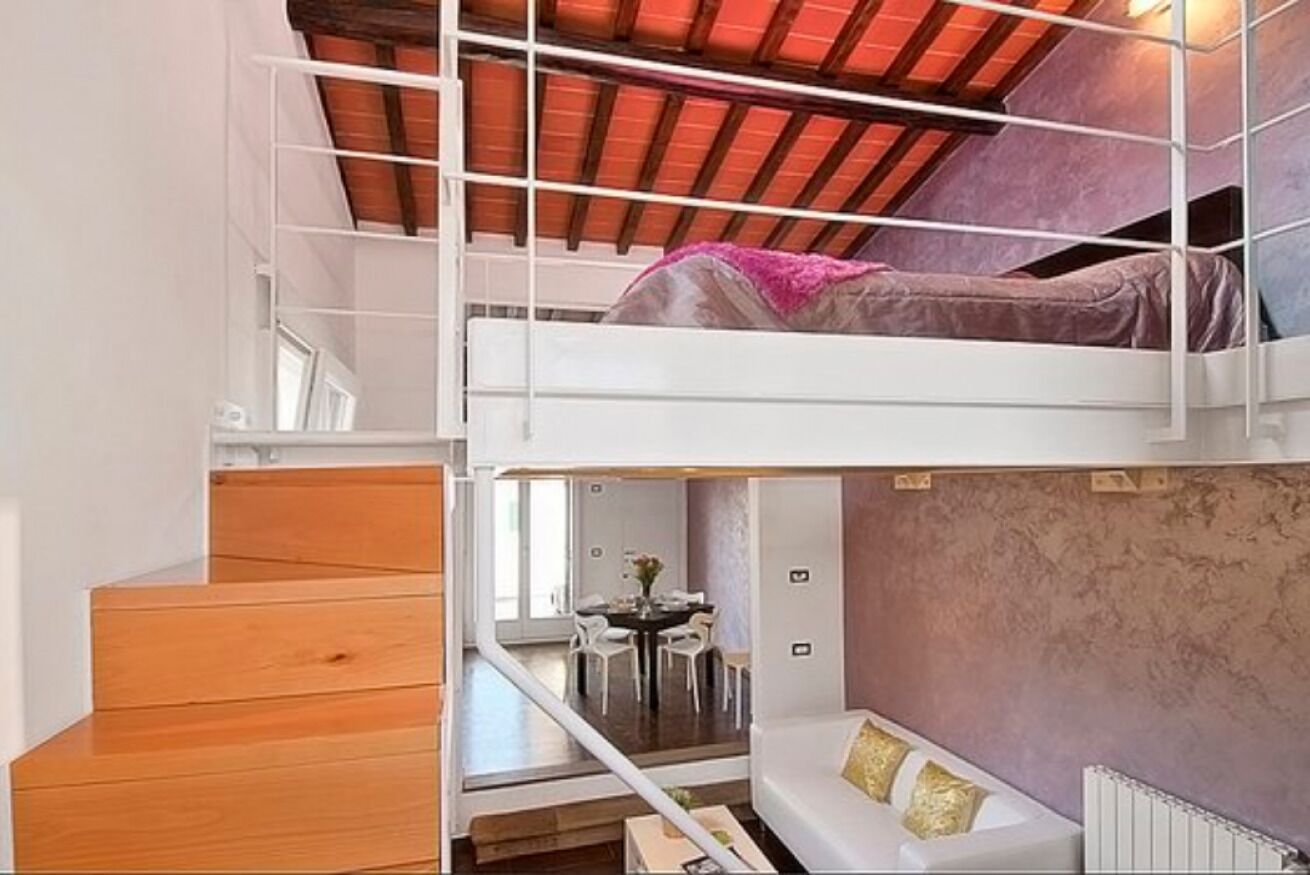 Habitación de varios niveles con literas, una escalera, zona de comedor y sofá.