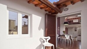A room with a wooden ceiling, a window, a door, and a dining area with chairs. - Apartments Florence San Gallo Suite VII with balcony (Florence)