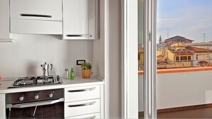 A kitchen with white cabinets, a gas stove, and a view of buildings through a balcony door. - Apartments Florence San Gallo Suite VII with balcony (Florence)