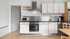 Una cocina moderna con armarios blancos, electrodomésticos de acero inoxidable y una mesa de comedor de madera.