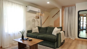 Una sala de estar moderna con un sofá verde, una mesa de centro de madera y un espejo grande.