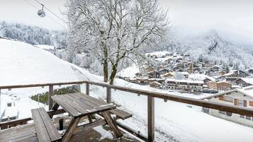 A wooden deck with a picnic table and a snow-covered village in the background.