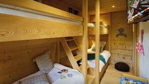 A wooden cabin interior with bunk beds, a ladder, and a television displaying a nature scene. - Le Petit Capricia - Aravis mountain stay for 8 - OVO Network (La Clusaz)