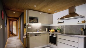 A modern kitchen with a built-in oven, microwave, and stainless steel range hood. - Le Petit Capricia - Aravis mountain stay for 8 - OVO Network (La Clusaz)