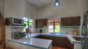 Une cuisine dotée d’un îlot central, de meubles en bois, d’un four à micro-ondes et d’une cuisinière à gaz.