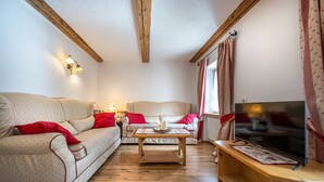 A cozy living room with a sofa, a coffee table, and a television. - Apartments Smidl 110D (Ortisei)