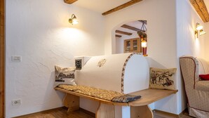 A cozy room with a wooden bench, a small table, and a sofa with patterned cushions. - Apartments Smidl 110D (Ortisei)