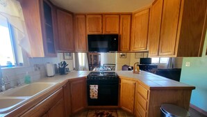 A kitchen with wooden cabinets, a stove, a microwave, and a sink. - The Getaway (Placerville)