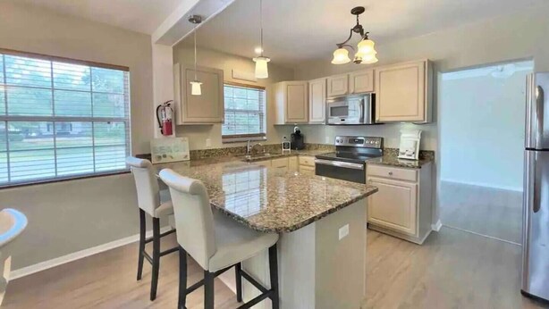 A modern kitchen with granite countertops, stainless steel appliances, and a central island with bar stools. - Prime Location, 2 Bath/2 Bed Perfect Getaway (Dunedin)