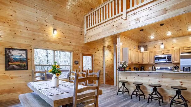 A wooden cabin interior with a dining area, kitchen, and bar stools. - Newly built Luxury cabin with a Game Room, Private Indoor Pool, Hot Tub, Theater (Gatlinburg)