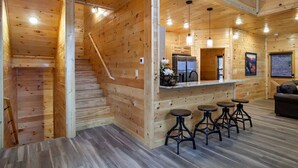 A wooden interior with a kitchen, bar area, and seating. - Newly built Luxury cabin with a Game Room, Private Indoor Pool, Hot Tub, Theater (Gatlinburg)