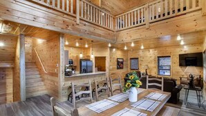 A wooden cabin interior with a dining area, kitchen, and living space. - Newly built Luxury cabin with a Game Room, Private Indoor Pool, Hot Tub, Theater (Gatlinburg)
