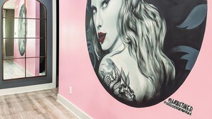 Un couloir avec une grande fresque murale circulaire, un miroir et un plancher en bois.