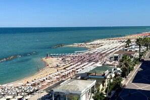 A beach with rows of umbrellas and beach chairs, a clear sky, and a calm sea. - P022 - Porto Recanati, brand new two-room apartment (Porto Recanati)
