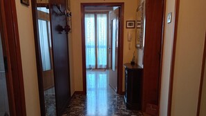 A hallway with a marble floor, wooden doors, and a small table with a telephone. - SE118 - Senigallia, large three-room apartment with balcony (Senigallia)