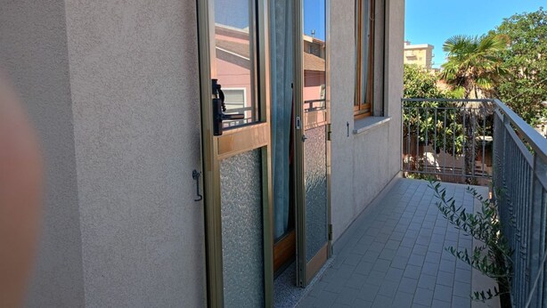 A balcony with a metal railing, a sliding glass door, and a tiled floor. - SE118 - Senigallia, large three-room apartment with balcony (Senigallia)
