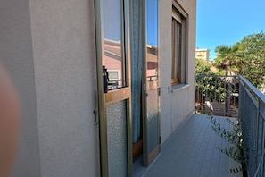 Un balcon doté d’une rambarde en métal, d’une porte-fenêtre coulissante et d’un sol carrelé.