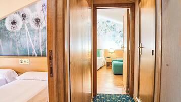 Quarto de hotel com uma cama, mesa de cabeceira e painel de controle fixado na parede.