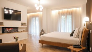 Ein modernes Hotelzimmer mit einem großen Bett, einem flachbildfernseher an der Wand, einem kleinen Tisch mit Fernbedienung und einer dekorativen Vase mit Blumen.