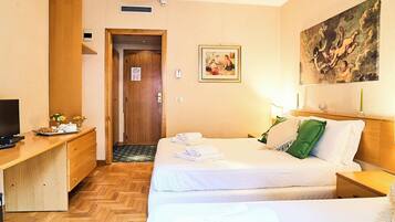 Habitación de hotel con dos camas, un escritorio, un televisor y un cuadro en la pared.
