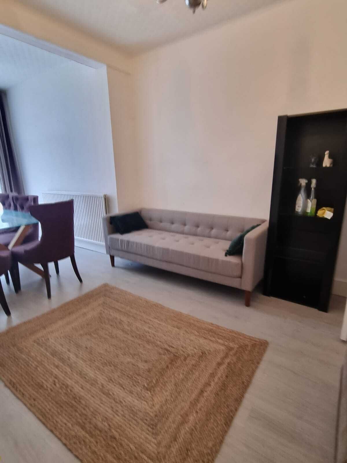 A modern living room with a beige sofa, a dark wooden coffee table, and a brown rug.
