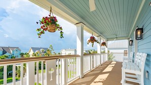 A covered porch with white railings, hanging flower baskets, and white benches. - Beach Access Directly Across Street! Ocean view, Private Pool, Hot Tub, Luxe New Construction (Isle Of Palms)