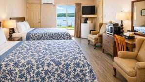 A hotel room with two beds, a television, a coffee bar, and a view of the water.
