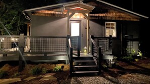 Uma casa com varanda, escada e área cercada.