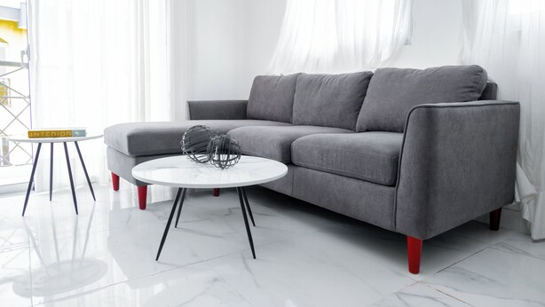 A modern living room with a grey sofa, a white round coffee table, and a small side table with a book titled "INTENTION". - Apartahotel Señorial (Higuey)