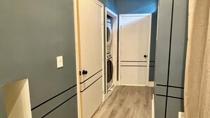 Un pasillo estrecho con suelo de madera y puertas que dan a habitaciones.