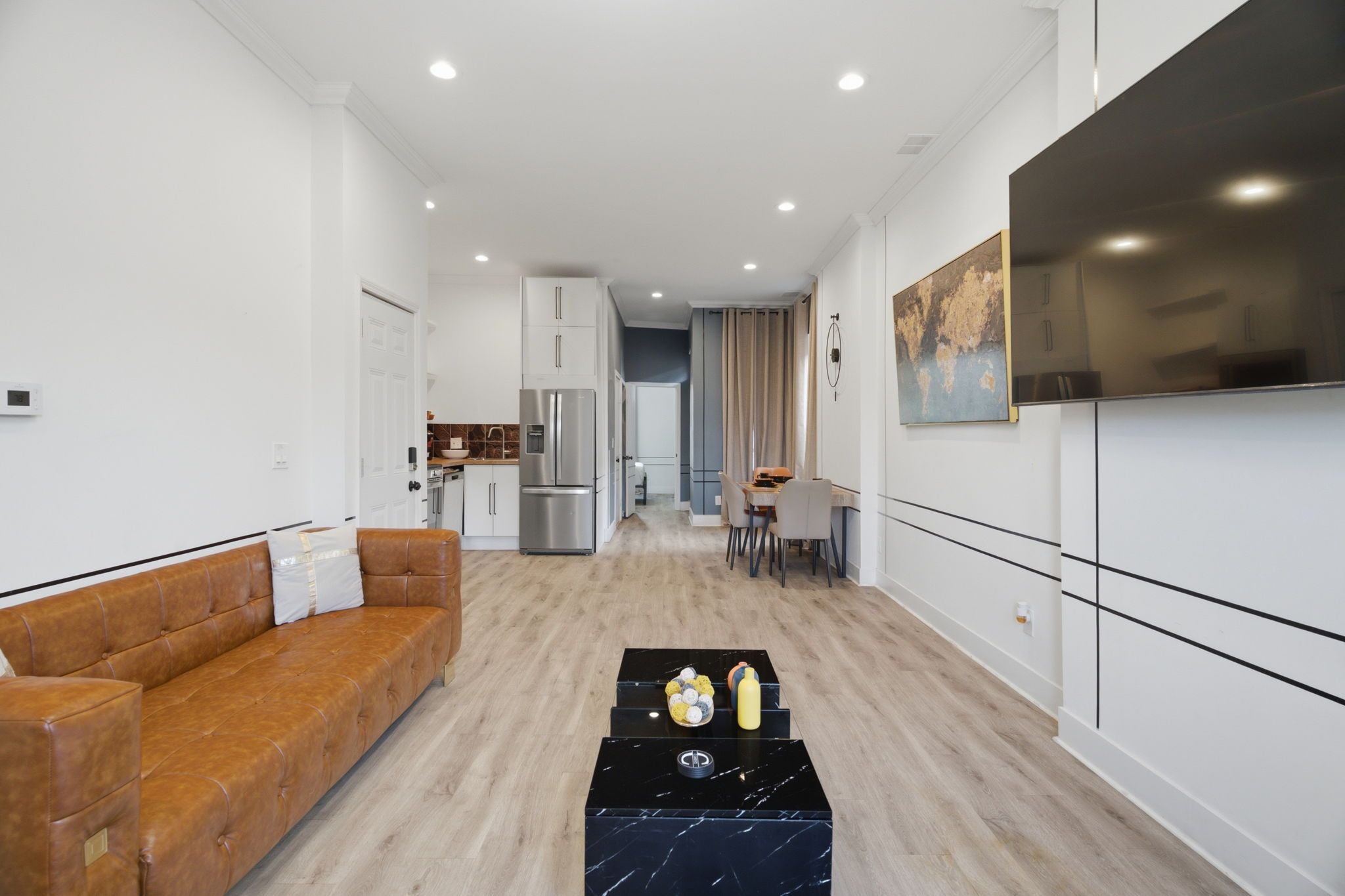 A modern living room with a sofa, a coffee table, and a TV mounted on the wall.