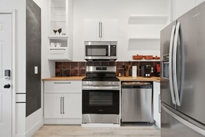 Une cuisine moderne dotée d’appareils électroménagers en acier inoxydable, de meubles blancs et d’un plan de travail en bois.
