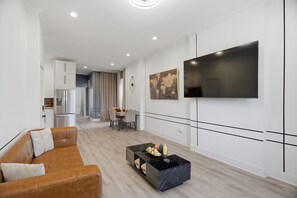 Een moderne woonkamer met een leren bank, een salontafel en een flatscreen televisie aan de muur.