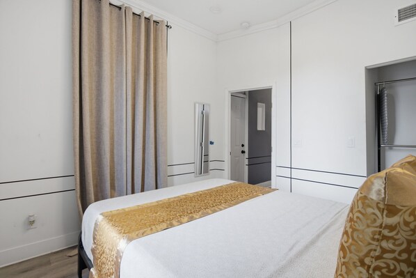Een hotelkamer met een bed, een kledingkast, een deur en een gordijn.