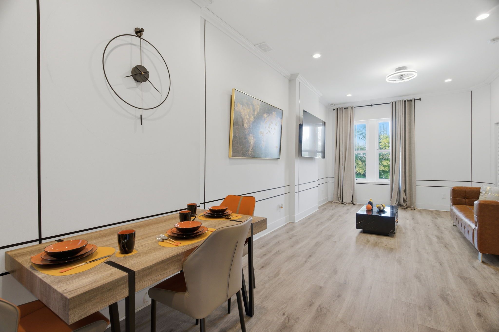 A modern dining area with a wooden table set for four, a sofa, and a coffee table.