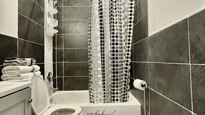 Un baño con bañera, inodoro y cortina de ducha.