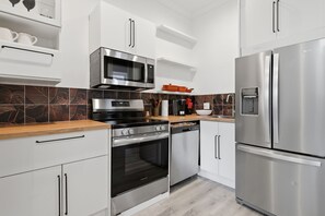 Een moderne keuken met roestvrijstalen apparatuur, witte kastjes en een decoratieve spatwand.