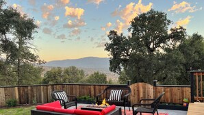 An outdoor patio with wicker furniture, a fire pit, and a view of the mountains.