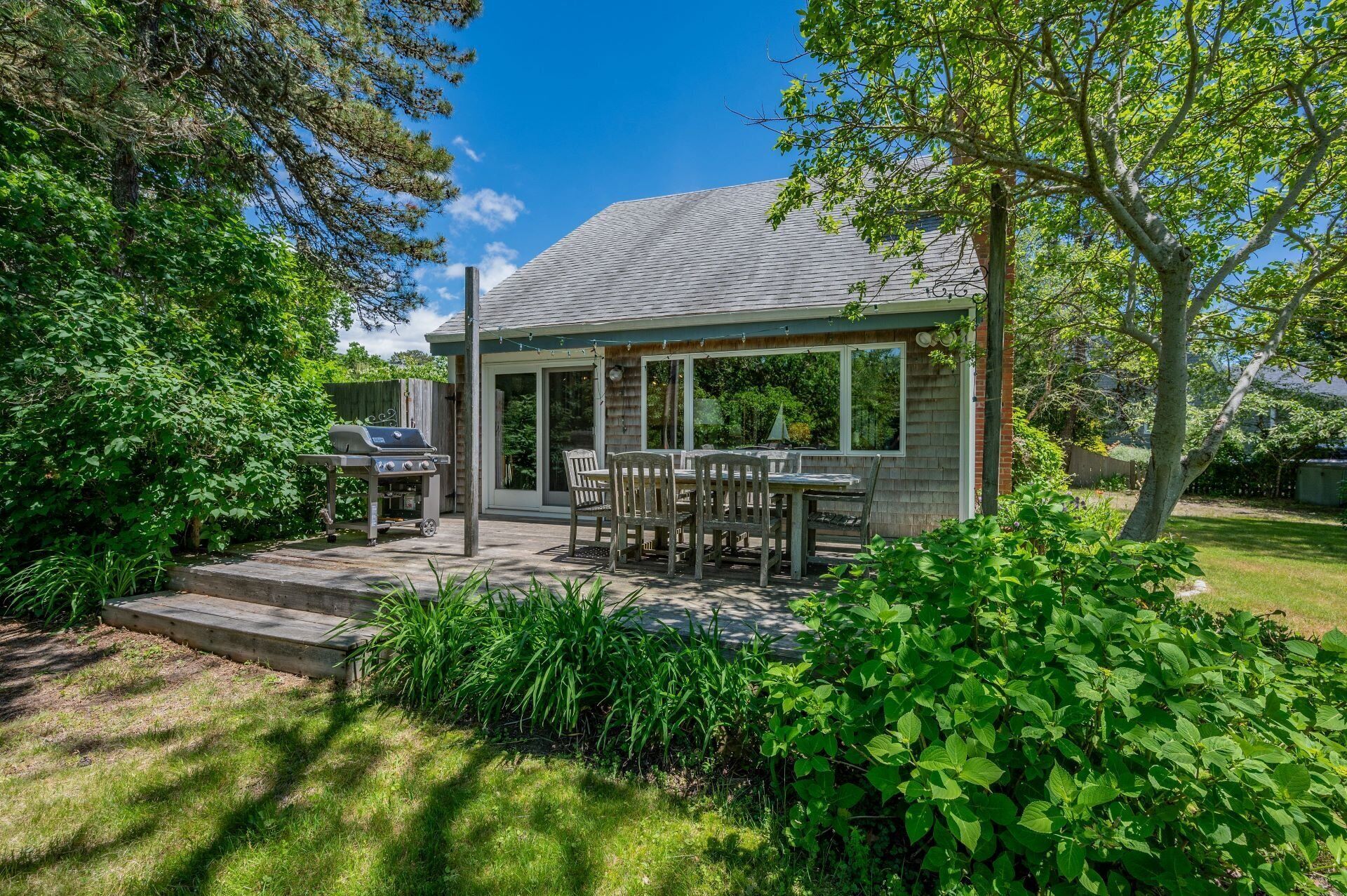 Ett hus med en täckt uteplats, en grill och en matplats med utemöbler.