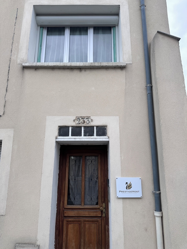 A building with a numbered door, a window with curtains, and a sign for 'PrestigeHost'.