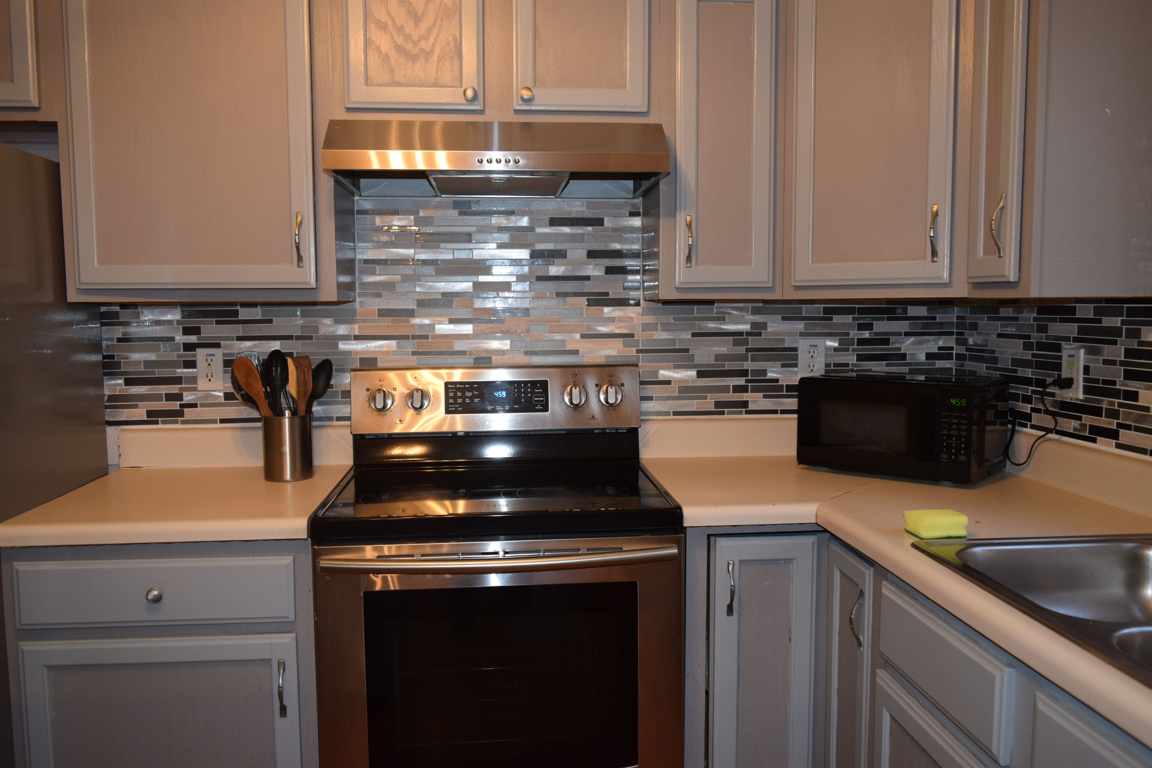 A kitchen with stainless steel appliances, a tiled backsplash, and light-colored cabinets. - Charming 4-bedroom house in welcoming Greenville with WiFi, AC (Greenville)