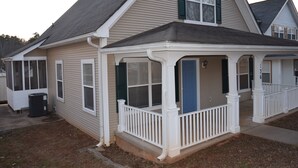 A two-story house with a covered porch, a garage, and a visible trash can. - Charming 4-bedroom house in welcoming Greenville with WiFi, AC (Greenville)